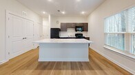 Located at 4035 Flat Shoals Pkwy in Decatur, GA, this well-designed 2-bedroom, 3-bathroom single-floor home offers a clean, modern layout with thoughtful finishes throughout. The kitchen serves as a central highlight, featuring a large marble-topped island, dark cabinetry, light wood-look flooring, recessed lighting, and black appliances including a refrigerator, range, and microwave. The open layout allows natural light to flow in through nearby windows, enhancing the bright, airy atmosphere. Both bedrooms are carpeted and feature ceiling fans, large windows with blinds offering views of surrounding trees, and generous closet space. The primary bedroom includes an en-suite bathroom with a dark-cabinet vanity topped with a marble-style countertop, a shower-tub combo, and wood-look flooring, along with a walk-in closet equipped with built-in shelving for organized storage. Hallways and transitional spaces also feature wood-look flooring, maintaining a cohesive aesthetic throughout. The two additional bathrooms provide ample accommodation for guests and residents alike. With neutral wall tones, clean white trim, and panel-style doors, the home presents a consistent, modern palette that is both functional and inviting.