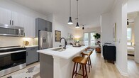 This thoughtfully designed one-bedroom, one-bathroom residence offers a cohesive open-concept layout that maximizes every square foot. The kitchen serves as the heart of the home, featuring two-tone grey cabinetry, stainless steel appliances, a subway tile backsplash, and a white quartz peninsula with seating for two — ideal for casual dining or entertaining. Pendant lighting with matte black fixtures adds a modern touch overhead. Light wood-tone flooring flows seamlessly throughout the space, enhancing the bright, airy atmosphere. The living room opens directly to the outdoors through glass French doors, filling the space with natural light and providing views of the surrounding greenery. Crown molding adds a refined architectural detail throughout. The bedroom is a calm retreat, highlighted by a striking blue accent wall, large windows with outdoor views, and warm, neutral tones. A dedicated closet and hallway provide practical storage. The bathroom features grey cabinetry with matte black hardware, a white quartz vanity, a full tub-shower combo with tile surround, and clean, contemporary finishes. Together, each room reflects a modern yet inviting design aesthetic built for comfortable everyday living.