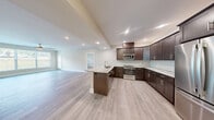 Located at 4805 W Genesee St in Syracuse, NY, this well-appointed 2-bedroom, 2-bathroom unit offers a thoughtfully designed single-floor layout with modern finishes throughout. Light wood-style flooring flows seamlessly across the living spaces, creating a clean and cohesive aesthetic.

The open-concept kitchen and living area serves as the heart of the home. The kitchen is outfitted with rich dark espresso cabinetry, marble-look granite countertops, a herringbone tile backsplash, a large center island with an undermount sink, and a full suite of stainless steel appliances including a refrigerator, range, microwave, and dishwasher. Recessed lighting illuminates the space effectively.

The spacious living room features large windows that invite natural light and a multi-blade ceiling fan, lending the room an airy feel. The generously sized primary bedroom connects to a private en-suite bathroom finished with marble-look tile flooring, a dark wood vanity with granite countertops, a tall storage tower, and a glass-enclosed shower. The second bedroom includes a double sliding-door closet and easy access to the second full bathroom, which also features marble-look tile and a granite vanity. A dedicated in-unit laundry room houses a full-size washer and dryer alongside additional cabinetry and countertop space.