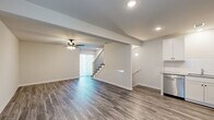 Located at 21256 W 216th Terrace in Spring Hill, Kansas, this tri-level home offers six bedrooms and four bathrooms spread across three thoughtfully arranged floors. The main living level features an open-concept kitchen and living room combination with durable wood-look luxury vinyl plank flooring, recessed lighting, and a ceiling fan. The kitchen is outfitted with crisp white cabinetry, a subway tile backsplash, stainless steel appliances including a refrigerator, range, and microwave, and ample counter space. The adjacent living area provides a bright, welcoming atmosphere with a sliding glass door that invites natural light. The bathrooms are finished with white vanity cabinetry, neutral countertops, and matching LVP flooring; one features a walk-in glass-door shower with chrome fixtures. Bedrooms are distributed across the upper and lower floors, with some showcasing vaulted ceilings, ceiling fans, and carpet flooring, while others feature LVP and natural window light. The primary bedroom is generously sized with its own dedicated space. The lower floor offers additional flexible living or bedroom space with LVP flooring and recessed lighting. Staircases connect all three levels, creating a cohesive and functional flow throughout this well-appointed home.