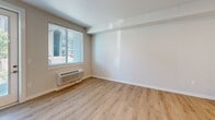 Located at 917 SW 31st St in Battle Ground, Washington, this one-bedroom, one-bathroom unit offers a well-designed, single-level layout with modern finishes throughout. Light wood-tone flooring runs seamlessly across the entire unit, creating a cohesive and clean aesthetic.

The kitchen is a standout feature, equipped with rich dark wood cabinetry, stainless steel appliances including a refrigerator, range, microwave, and dishwasher, and a generous white quartz island that provides ample prep and dining space. Recessed lighting illuminates the kitchen and flows into the adjoining living area, which benefits from natural light through large windows fitted with horizontal blinds and a glass door that opens to the exterior.

The bedroom offers a comfortable footprint with a ceiling fan, a wide sliding-door closet for storage, and a window overlooking the surrounding community, allowing in plenty of natural light. A wall-mounted HVAC unit ensures year-round climate control in the living area.

The bathroom maintains the unit's modern character with a wood-toned vanity, white quartz countertop, undermount sink, a large mirror, and clean white walls. The overall design is contemporary and functional, with a neutral color palette that provides a bright and inviting atmosphere throughout.