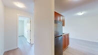 Located at 7185 Hall Rd in Surrey, BC, this one-bedroom unit offers a practical and comfortable single-floor layout. Light-toned laminate flooring runs throughout the space, creating a cohesive and clean aesthetic that brightens each room.

The living room is a generous, open area featuring a fireplace and a sliding glass door that leads to a private balcony, allowing natural light to fill the room and offering views of surrounding greenery. A baseboard heating system is present along the perimeter.

The kitchen is efficiently designed with rich warm-toned cabinetry, stainless steel appliances including a refrigerator, and a countertop workspace. It is partially separated from the living area by a structural column, creating a defined yet connected cooking space.

The bedroom is a well-sized room with a large window framing a pleasant outdoor tree view, and is equipped with a built-in closet featuring bifold doors, providing ample storage. The neutral walls and light flooring contribute to a calm, restful ambiance.

Overall, the unit presents a clean, move-in-ready environment with a practical layout suited for comfortable everyday living in the Newton area of Surrey.