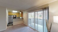 Located at 11733 NE 131st Place in Kirkland, Washington, this single-floor residence offers a well-organized layout designed for comfortable everyday living. The open-concept living and dining area is finished with plush carpeting and a textured ceiling, creating a warm and inviting atmosphere. Large sliding glass doors lead directly to a private outdoor deck, framing peaceful views of surrounding trees and lush Pacific Northwest greenery, and flooding the interior with generous natural light.

The kitchen is positioned adjacent to the living area and features warm wood-toned cabinetry, stainless steel appliances including a refrigerator and microwave, an electric range, and a countertop bar that connects the two spaces seamlessly. Wood-look flooring adds a clean, practical finish underfoot.

The bedrooms are carpeted and well-proportioned, with one featuring dual mirrored sliding closet doors that enhance the sense of space. Multiple windows allow natural light to fill the rooms, with views of the surrounding greenery. The bathroom includes a full tub and shower combination, wood-look flooring, and a vanity with contemporary fixtures. Throughout the home, a neutral color palette and clean finishes contribute to a cohesive and functional living environment.