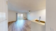 This 340 square foot apartment in Newport Beach, CA, offers a thoughtful layout maximizing its compact space. The open-concept living area boasts hardwood flooring, creating a warm and inviting atmosphere. A ceiling fan provides comfort and air circulation, while a sliding glass door leads to a private balcony, offering views of the well-maintained complex grounds.

The kitchen, though not fully visible, appears to feature bright yellow cabinetry, adding a pop of color to the neutral palette. The bathroom is efficiently designed with a full-sized bathtub/shower combination and modern fixtures. Wall-mounted air conditioning ensures year-round comfort.

The balcony overlooks a beautifully landscaped courtyard with lush greenery and a central water feature, providing a serene outdoor space for residents. The apartment complex itself showcases a clean, contemporary architectural style with multiple buildings surrounding the central garden area.

This space is ideal for those seeking a low-maintenance lifestyle in a prime Newport Beach location, offering a perfect blend of indoor comfort and outdoor amenities.