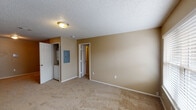 This single-floor, 1-bedroom, 1-bathroom unit offers a practical and comfortable layout designed to maximize everyday living. The kitchen is outfitted with warm-toned wood cabinetry featuring raised-panel doors, light granite-style countertops, stainless steel appliances including a refrigerator, electric range with vent hood, and dishwasher, along with a double-basin stainless steel sink — providing both function and style in a compact, efficient space. Light wood-style flooring runs through the kitchen, complementing the neutral warm-beige walls found throughout the unit. The main living area is generously sized with plush carpeting, textured ceilings, and a full-light entry door that brings in natural light. An accent wall with vertical paneling adds a subtle architectural detail. The bedroom offers carpeted flooring, a window with blinds for natural light, and direct access to a walk-in closet. A dedicated laundry closet with stacked washer and dryer is conveniently located off the bedroom. The bathroom features a tub/shower combination with white tile surround, hardwood-style flooring, a vanity, and towel bars. This unit delivers a complete, move-in-ready living experience within a compact and efficient footprint.