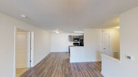 This single-floor residence offers a thoughtfully arranged open-concept layout that connects the living area and kitchen seamlessly. The living space features warm wood-style plank flooring, crisp white walls, and a ceiling fan, creating a bright and comfortable environment. A sliding glass door opens to a private outdoor area, allowing natural light to fill the room.

The kitchen is designed for functionality, featuring dark espresso-toned cabinetry, light stone-finish countertops, and a full suite of black appliances including a range, microwave, and refrigerator. A peninsula counter separates the kitchen from the living area, providing additional workspace and a casual dining option.

The bathroom includes a dual-sink vanity with dark wood cabinetry, brushed nickel fixtures, framed mirrors, and wood-style flooring. A second bathroom offers a tiled shower-tub combination with brushed nickel hardware. The bedroom is carpeted and features a ceiling fan and a window providing natural light.

A dedicated laundry room houses a full-size washer and dryer with overhead dark wood cabinetry for added storage. Throughout the unit, consistent finishes and neutral tones create a cohesive and modern aesthetic.
