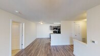 This single-floor residence offers a thoughtfully arranged open-concept layout that connects the living area and kitchen seamlessly. The living space features warm wood-style plank flooring, crisp white walls, and a ceiling fan, creating a bright and comfortable environment. A sliding glass door opens to a private outdoor area, allowing natural light to fill the room.

The kitchen is designed for functionality, featuring dark espresso-toned cabinetry, light stone-finish countertops, and a full suite of black appliances including a range, microwave, and refrigerator. A peninsula counter separates the kitchen from the living area, providing additional workspace and a casual dining option.

The bathroom includes a dual-sink vanity with dark wood cabinetry, brushed nickel fixtures, framed mirrors, and wood-style flooring. A second bathroom offers a tiled shower-tub combination with brushed nickel hardware. The bedroom is carpeted and features a ceiling fan and a window providing natural light.

A dedicated laundry room houses a full-size washer and dryer with overhead dark wood cabinetry for added storage. Throughout the unit, consistent finishes and neutral tones create a cohesive and modern aesthetic.