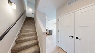 Located at 8421 Mansion Hill Ave in Madison, Wisconsin, this two-floor residence offers a thoughtfully designed layout spread across a generously sized main level and a lofted upper level. The main floor commands attention with its dramatically tall ceilings and an abundance of natural light, enhanced by large sliding glass doors that open onto a private balcony overlooking lush greenery. A wall-mounted mini-split climate system provides efficient heating and cooling throughout. Light hardwood-style flooring runs throughout the main level, lending a clean, contemporary aesthetic. The kitchen is a standout feature, equipped with stainless steel appliances including a refrigerator, electric range, and microwave, all complemented by rich dark wood cabinetry, white quartz countertops, a peninsula with an undermount sink, and matte black fixtures. The bathroom is finished with a full soaking tub and shower combo, wood-look flooring, and matte black hardware accents. A hallway connects the main living areas efficiently. Upstairs, the lofted upper level features plush carpeting, a ceiling fan with light, a double-door closet, and an open railing overlooking the main floor below, creating a sense of openness and connectivity between levels.