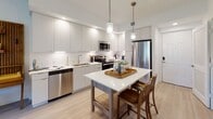 This well-appointed one-bedroom, one-bathroom residence at 400 SW 27th Ave offers a thoughtfully designed single-floor layout with modern finishes throughout. The kitchen is a standout feature, showcasing floor-to-ceiling white cabinetry, white quartz countertops, stainless steel appliances including a refrigerator, range, microwave, and dishwasher, and light wood-style flooring that flows seamlessly through the space. A central kitchen island with seating provides additional prep and dining space, while pendant lighting adds a warm, contemporary touch. The open-concept layout connects the kitchen to the dining area and living room, creating an airy, cohesive living space. The living room is bathed in natural light from large sliding glass doors that open directly to a private patio, offering serene garden and greenery views. The bedroom is generously proportioned, featuring light wood flooring, sheer curtains, a ceiling fan, and ample natural light from a large window. A convenient in-unit stacked washer and dryer is tucked neatly within the unit. Clean white walls, gold accent hardware, and a cohesive neutral palette give the entire residence a fresh, modern aesthetic that is both functional and stylish.