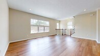 Located in Milford, Ohio, this well-appointed three-story home offers a thoughtfully designed layout across three distinct levels. The ground floor houses a generously sized garage with an automatic opener, providing convenient interior access, along with additional utility space. The main living level serves as the heart of the home, featuring a bright living room with gleaming hardwood floors, large windows that flood the space with natural light, and an open staircase with classic wood and iron railings. The kitchen is outfitted with warm wood cabinetry, stainless steel appliances including a full-size refrigerator, range, and microwave, all complemented by hardwood flooring. A full bathroom on this level features rich wood vanity cabinetry with granite-style countertops. The upper floor hosts three bedrooms, including a spacious primary suite with vaulted ceilings, a ceiling fan, plush carpeting, and a walk-in closet with built-in shelving. Additional bedrooms are carpeted and offer ample natural light through large windows with neighborhood views. Carpeted staircases with wood handrails connect all three levels smoothly. A balcony and den round out the home's versatile living spaces, creating a comfortable and functional residence suited for everyday living.