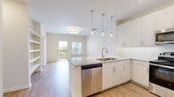 Located at 131 Great Circle Rd in Nashville, TN, this well-appointed one-bedroom, one-bathroom residence offers a thoughtfully designed open-concept layout that maximizes its comfortable footprint. The kitchen and living area flow seamlessly together, anchored by a central island with granite countertops and a double sink, illuminated by elegant pendant lighting. White shaker-style cabinetry pairs with a full suite of stainless steel appliances — including a range, over-the-range microwave, dishwasher, and French door refrigerator — to create a polished, modern kitchen. Wood-style flooring runs throughout the main living areas, adding warmth and continuity. The living room is filled with natural light from large windows and a sliding glass door that opens to a private balcony with outdoor views. The spacious bedroom features plush carpeting, a ceiling fan, and a window overlooking the surrounding greenery. A well-sized walk-in closet with wire shelving provides generous storage. The bathroom is finished with granite countertops, white cabinetry, a large mirror, and wood-style flooring. A dedicated in-unit laundry area adds everyday convenience, completing this functional and stylish Nashville residence.