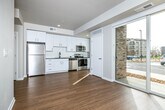 This single-floor residence at 1601 NW 38th St in Kansas City, Missouri offers a clean, contemporary design highlighted by light hardwood flooring, crisp white walls, and an open, airy layout. The living area is bathed in natural light through large sliding glass doors that open to views of the surrounding neighborhood, creating a seamless connection between interior and exterior spaces.

The kitchen is thoughtfully designed with sleek white cabinetry, dark countertops, a classic subway tile backsplash, and a full suite of stainless steel appliances including a refrigerator, range, and over-the-range microwave. A tall window beside the range further brightens the space and adds to the sense of openness.

A stylish barn-style sliding door provides access to a private room featuring carpeted flooring, offering a soft contrast to the hardwood found throughout the main living areas. The bathroom is appointed with a dark granite countertop, an undermount sink, white cabinetry, and a tiled walk-in shower with grab bar, combining functionality with modern aesthetics.

Throughout the unit, recessed lighting, clean lines, and a neutral color palette work together to create a bright, welcoming ambiance well-suited to contemporary living in the heart of Kansas City.