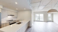 Located at 308 Rue Crevier in Saint-Laurent, Québec, this contemporary 2-bedroom, 1-bathroom unit offers a well-appointed layout across a single floor. The open living area makes a striking impression with its exposed concrete ceiling, light wood-tone flooring, and crisp white walls that create a clean, modern industrial aesthetic. A wall-mounted mini-split unit provides climate control, complementing the baseboard heating found throughout.

The kitchen is a functional highlight, featuring a large peninsula with a quartz-style countertop and integrated sink, two-tone cabinetry with wood-grain lower panels and white uppers, stainless steel appliances including a full-size refrigerator and range, and recessed lighting overhead.

Both bedrooms benefit from large windows that flood the rooms with natural light and offer views of the surrounding Saint-Laurent neighbourhood. The exposed concrete ceiling extends into the bedrooms, maintaining the unit's cohesive industrial-modern character. A closet provides additional storage.

The bathroom is bright and well-designed, with a floating white vanity, large-format grey tile flooring, a mirrored medicine cabinet, and a glass-enclosed combination tub and shower. The overall ambiance throughout is clean, minimal, and move-in ready.