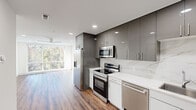 Located at 490p Spruce St in Philadelphia's West Philadelphia neighborhood, this modern 2-bedroom, 2-bathroom residence offers a thoughtfully designed single-floor layout with contemporary finishes throughout. Warm hardwood-style flooring flows seamlessly across every room, complementing the bright, neutral palette that defines the space.

The open-concept kitchen and living area serves as the heart of the home. The kitchen is outfitted with high-gloss gray upper cabinetry, crisp white lower cabinets, a marble-style quartz backsplash and countertops, and a full suite of stainless steel appliances including a refrigerator with ice maker, electric range, built-in microwave, and dishwasher. Large floor-to-ceiling windows in the living area flood the space with natural light and offer tree-lined views of the surrounding neighborhood.

Both bedrooms are generously proportioned, each featuring oversized windows that frame lush treetop and rooftop views, recessed lighting, and ceiling fans. The primary bedroom provides a comfortable and well-lit retreat with abundant natural light.

The two bathrooms showcase elegant marble-style tile throughout, with one featuring a glass-enclosed walk-in shower and the other a tub-shower combination with sliding glass doors. Recessed lighting and clean white finishes give both bathrooms a spa-like feel. A dedicated closet provides additional storage within the unit.