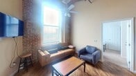 This expansive 1310 square foot apartment in York, PA, offers a unique living experience with its blend of industrial and modern design elements. The space boasts five bedrooms, three bathrooms, and an open-concept kitchen and living area, all conveniently arranged on a single floor.

Upon entering, you're greeted by the striking exposed brick walls that add character and warmth to the living spaces. The high ceilings, accentuated by exposed beams and ductwork, create an airy, loft-like atmosphere throughout. Large windows allow ample natural light to flood the rooms, enhancing the sense of spaciousness.

The kitchen is a standout feature, with its modern white cabinetry, stainless steel appliances, and a practical island that doubles as a breakfast bar. The adjacent living area, with its hardwood floors and ceiling fan, offers a comfortable space for relaxation and entertainment.

The bedrooms are generously sized, with the primary bedroom measuring 180 square feet. Each room features large windows and ample closet space. The bathrooms are clean and functional, with modern fixtures and tiled floors.

Throughout the apartment, you'll find a harmonious blend of industrial elements and contemporary comforts, creating a unique and inviting living space. The 1310 square feet are utilized efficiently, offering both privacy in the bedrooms and openness in the common areas, making this apartment an ideal home for those seeking a distinctive urban living experience.