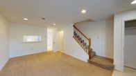 This two-floor residence offers a practical and comfortable layout across both levels. The main living area is bright and open, finished with plush wall-to-wall carpeting and recessed lighting. A classic staircase with a warm wood banister and white spindles connects the two floors, adding a traditional architectural touch. The kitchen is well-equipped, featuring warm honey-toned wood cabinetry, white appliances including an electric range, built-in microwave, dishwasher, and a full-size refrigerator. Light countertops provide ample workspace, and a pass-through window connects the kitchen to the adjacent living area, enhancing the sense of openness. The bedroom offers generous space with natural light flowing in through multiple windows dressed with horizontal blinds. A standout feature is the dual closet configuration, providing abundant storage with full-length hanging rods. Baseboard heating is present throughout the upper level. The full bathroom is clean and functional, complete with a wood vanity, white countertop, tiled tub-shower combination, and light tile flooring. Recessed lighting and neutral white walls throughout the home create a bright, move-in-ready atmosphere suited for a variety of living arrangements.