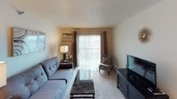 This single-floor unit offers a practical and comfortable layout with two bedrooms, one bathroom, and a well-organized living space. The galley-style kitchen features white cabinetry with wood-tone accents, white appliances including a coil-top range, dishwasher, and refrigerator, complemented by light countertops and easy-care vinyl flooring. Adjacent to the kitchen, a dedicated dining area provides space for a full dining set and includes a ceiling fan overhead.

The carpeted living room is a comfortable gathering space with a sliding glass door that allows natural light to fill the room. The two bedrooms are carpeted and each includes a ceiling fan with light fixture. One bedroom features a sliding closet and an additional door, while the second bedroom is served by a window with blinds. Both rooms offer a calm, neutral atmosphere with textured ceilings throughout the unit.

The single full bathroom includes a tub-shower combination with a curtain rod, a toilet, and tile-style flooring, with a linen storage cabinet nearby. Overall, the unit presents a straightforward, functional floor plan suited for everyday living.