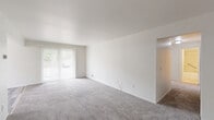 Located at 34659 Mulvey Road in Fraser, Michigan, this single-floor, two-bedroom, one-bathroom residence offers a functional and straightforward layout ideal for comfortable everyday living. The open living room is a standout feature, boasting plush wall-to-wall carpeting, bright white walls, and a large sliding glass door fitted with vertical blinds that flood the space with natural light and provide outdoor views. The living area flows into a dedicated dining room and a separate kitchen equipped with cabinetry, maintaining a clear distinction between living and cooking spaces. A connecting hallway leads to both bedrooms, each carpeted and finished with clean white walls. The primary bedroom offers generous proportions and features a built-in double closet, while the second bedroom includes its own window with vertical blinds and a ceiling light fixture. Notably, the unit includes six closets in total, providing exceptional storage capacity throughout. The bathroom is appointed with a full tub-and-shower combination, white square tile surround, and stainless steel grab bars. Ceiling-mounted HVAC vents are present throughout the home, ensuring year-round climate comfort. The overall aesthetic is clean, neutral, and move-in ready.
