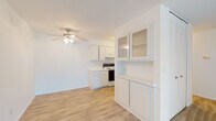 This single-floor unit offers a bright, functional layout designed for comfortable everyday living. The open-concept kitchen and living area forms the heart of the space, featuring light wood-look flooring that extends throughout the common areas. The kitchen is well-appointed with white cabinetry — including glass-front upper cabinet doors — white countertops, a full suite of appliances including an electric range, dishwasher, and refrigerator, and ample storage both above and below the counter. A ceiling fan with integrated lighting serves the adjacent living area, which flows seamlessly from the kitchen and is bathed in natural light through vertical-blind-covered sliding glass doors that open to the outdoors.

The bedroom is generously sized, carpeted for added comfort, and features a window with vertical blinds for natural light and privacy. A spacious walk-in closet provides excellent storage. The bathroom is finished with wood-look flooring and includes a vanity, toilet, and a full bathtub with shower. Throughout the unit, crisp white walls and clean lines create a bright, airy atmosphere, offering a versatile canvas ready for personalization.