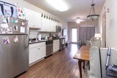 Located at 1914 University Blvd in Tuscaloosa, Alabama, this single-floor unit offers a practical and comfortable layout designed for everyday living. The kitchen is a standout feature, showcasing crisp white cabinetry with classic raised-panel detailing, dark granite countertops, and a full suite of stainless steel appliances including a refrigerator, dishwasher, electric range with an over-the-range microwave, and a double-basin sink. Warm hardwood-style flooring runs throughout the kitchen and connects seamlessly to the adjacent living areas, adding a cohesive and inviting feel. The bedroom is a calm retreat, featuring rich hardwood-style flooring, neutral-toned walls, and a ceiling fan with light fixture. A window dressed with light curtains allows natural light to filter in gently, enhancing the room's airy atmosphere. The full bathroom is finished with light tile flooring, a tub and shower combination with white tile surround, a toilet, and a vanity with ample counter space. The overall layout, as seen in the floorplan, flows efficiently, connecting the main living space, kitchen, bedroom, and bathroom in a compact and functional arrangement well-suited for comfortable residential living.