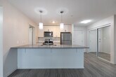 This well-appointed 2-bedroom, 1-bathroom unit at 772 Paisley Rd in Guelph, Ontario offers a thoughtfully designed layout with modern finishes throughout. The open-concept kitchen and living area serves as the heart of the unit, featuring a large island with a sleek grey quartz countertop and undermount sink, white cabinetry, a full suite of stainless steel appliances, and stylish pendant lighting. The living area is bright and airy, with large windows that invite natural light and provide outdoor views, complemented by light wood-look flooring that extends throughout the unit. A private balcony adds additional outdoor space. Both bedrooms are comfortably sized, finished with the same light flooring and windows, offering a clean, neutral palette. The bathroom features a white vanity with a large mirror and bright lighting, alongside a well-organized closet with built-in shelving. A dedicated in-unit laundry room provides added convenience with a full-sized washer and dryer. The hallway connects all rooms efficiently, with two closets offering generous storage. The unit's consistent use of neutral tones, modern fixtures, and functional spaces creates a clean and contemporary living environment.