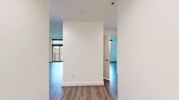Located at 900 NW Lovejoy St in Portland's vibrant Northwest District, this two-bedroom, one-bathroom unit offers a well-organized layout across a single floor. Hardwood-style flooring runs consistently throughout the living areas and bedrooms, creating a cohesive and clean aesthetic.

The living room is a bright, open space anchored by floor-to-ceiling sliding glass doors that lead to a private balcony, offering views of the surrounding Portland cityscape. Natural light fills the room, enhancing its airy feel.

The kitchen is thoughtfully appointed with warm-toned wood cabinetry, granite countertops, and a full suite of stainless steel appliances including a refrigerator, electric range, microwave, and dishwasher — providing both functionality and style.

The primary bedroom is generously sized, featuring large windows with urban views and ample wall space. The second bedroom also benefits from natural light through a multi-pane window. A notable built-in shelving unit adds practical storage and a distinctive architectural touch.

The bathroom is finished with a white vanity, granite countertop, large mirror, and light tile flooring, maintaining the unit's clean, contemporary design. A hallway connects all rooms efficiently, completing this well-planned urban residence.