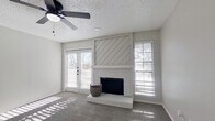 This efficiently designed single-floor, one-bedroom, one-bathroom home offers a thoughtful layout across a compact yet functional footprint. The living room serves as the heart of the space, highlighted by a white-painted brick fireplace with a diagonal shiplap accent surround that adds a farmhouse-inspired architectural detail. A ceiling fan overhead and French doors flanked by a large window invite abundant natural light and provide outdoor access, while carpet flooring adds warmth underfoot throughout the living and bedroom areas.

The kitchen features light gray wood-look vinyl plank flooring, white cabinetry, and standard appliances, flowing efficiently alongside a dedicated in-unit laundry area for added convenience. A closet provides practical storage within the layout.

The bedroom is a comfortable, well-proportioned room with soft carpeting, neutral gray walls, and ample wall space for flexible furniture arrangement.

The bathroom stands out as a stylish highlight, showcasing white shaker-style cabinetry, a white quartz countertop, an undermount sink, matte black hardware and fixtures, a round mirror, and wood-look vinyl plank flooring. The tub-shower combination with a clean white surround and black fixtures completes the space with a modern, cohesive aesthetic. The neutral color palette and updated finishes throughout give the home a clean, move-in-ready feel.