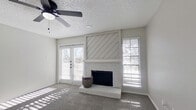 This efficiently designed single-floor, one-bedroom, one-bathroom home offers a thoughtful layout across a compact yet functional footprint. The living room serves as the heart of the space, highlighted by a white-painted brick fireplace with a diagonal shiplap accent surround that adds a farmhouse-inspired architectural detail. A ceiling fan overhead and French doors flanked by a large window invite abundant natural light and provide outdoor access, while carpet flooring adds warmth underfoot throughout the living and bedroom areas.

The kitchen features light gray wood-look vinyl plank flooring, white cabinetry, and standard appliances, flowing efficiently alongside a dedicated in-unit laundry area for added convenience. A closet provides practical storage within the layout.

The bedroom is a comfortable, well-proportioned room with soft carpeting, neutral gray walls, and ample wall space for flexible furniture arrangement.

The bathroom stands out as a stylish highlight, showcasing white shaker-style cabinetry, a white quartz countertop, an undermount sink, matte black hardware and fixtures, a round mirror, and wood-look vinyl plank flooring. The tub-shower combination with a clean white surround and black fixtures completes the space with a modern, cohesive aesthetic. The neutral color palette and updated finishes throughout give the home a clean, move-in-ready feel.