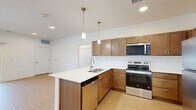 This single-story residence in Blair, Nebraska offers a thoughtfully designed layout encompassing three bedrooms, three bathrooms, a combined kitchen and living area, a hallway, and a dedicated closet. The open-concept kitchen is a standout feature, showcasing warm wood cabinetry, white subway tile backsplash, light quartz countertops, stainless steel appliances including a refrigerator, range, microwave, and dishwasher, and a central island with pendant lighting overhead. Light bamboo-style hardwood flooring runs throughout the main living and kitchen areas, contributing to a bright, cohesive aesthetic. The living room benefits from a sliding glass door that opens to a private balcony, allowing an abundance of natural light to fill the space. The primary bedroom is generously sized, featuring dual windows, a ceiling fan, plush carpeting, and a built-in closet. Additional bedrooms are carpeted and naturally lit, offering comfortable, versatile spaces. The primary bathroom includes a walk-in shower, wood vanity with white countertop, and modern brushed nickel fixtures, while secondary bathrooms feature full tub-shower combinations. Clean white walls and recessed lighting are consistent throughout, creating a modern and neutral ambiance well-suited to a variety of living arrangements.