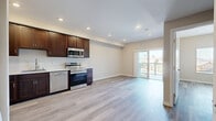 Located at 6916 Fulton St in San Diego, CA, this modern single-floor residence offers a clean, contemporary design throughout. The open-concept living and kitchen area is anchored by light-toned hardwood-style flooring that flows seamlessly through the entire unit, creating a cohesive and spacious feel. Recessed lighting illuminates the interior, complementing the natural light that pours in through a sliding glass door leading to a private balcony with neighborhood views.

The kitchen is well-appointed with rich dark-wood cabinetry, a full suite of stainless steel appliances including a range, microwave, dishwasher, and refrigerator, as well as a stainless steel sink. A stacked in-unit washer and dryer is conveniently located just off the kitchen, adding everyday practicality.

The bedroom area is bright and open, benefiting from a second sliding glass door that invites additional natural light and outdoor access. A walk-in closet provides generous storage with full hanging rods. The bathroom features matching dark-wood cabinetry, a white countertop vanity, wood-look tile flooring, and a window for natural ventilation. The unit's neutral color palette and clean finishes make it a versatile and move-in-ready space.