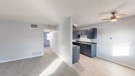 Located at 1905 W 40th St in Davenport, Iowa, this single-floor, 2-bedroom, 1-bathroom unit offers a practical and comfortable layout across a compact, efficiently organized floor plan. The living room provides a welcoming entry point, finished with neutral carpet and light blue-gray walls that carry consistently throughout the space, creating a cohesive, calm atmosphere. Natural light filters in through windows fitted with horizontal blinds, brightening the carpeted areas. The galley-style kitchen is a functional highlight, lined on both sides with dark navy-gray cabinetry, dark countertops, and tile flooring. It includes an electric range, a refrigerator, and a double sink, with ample upper and lower cabinet storage. A hallway connects the main living area to the two bedrooms and the bathroom. The primary bedroom offers a comfortable footprint with carpet flooring and a window providing natural light. The second bedroom, also carpeted, features a closet and is similarly finished. The full bathroom includes a white soaking tub with a tiled shower surround and a toilet. Ceiling-mounted vents throughout ensure consistent climate control. The textured ceilings and clean white trim complete the straightforward, move-in-ready aesthetic of this Davenport residence.