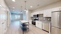 Located at 1112 S Grant Ave in Springfield, MO, this single-story, one-bedroom, one-bathroom unit offers a thoughtfully designed layout with modern finishes throughout. Light wood-look flooring flows seamlessly across the entire space, creating a cohesive and contemporary feel.

The open-concept kitchen and living area serves as the heart of the unit. The kitchen is equipped with stainless steel appliances — including a gas range, microwave, refrigerator, and dishwasher — complemented by white shaker-style cabinetry, granite countertops, and a gray tile backsplash. Stylish pendant lights hang above a freestanding island, while recessed lighting and a ceiling fan in the living area enhance both function and comfort. A large window allows natural light to fill the space, with an exterior door providing additional access.

The bedroom is a comfortable, well-proportioned room featuring a window with outdoor views and consistent flooring. It is accompanied by a dedicated walk-in closet with wire shelving for organized storage. The full bathroom features tile flooring, a granite-topped vanity, a walk-in shower, and clean, neutral finishes. Additional spaces include a laundry room and a utility room, rounding out a practical and well-appointed floor plan.
