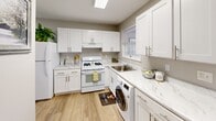 Located at 1700 RT 37 W in Toms River, NJ, this well-appointed 2-bedroom, 2-bathroom single-story home offers a thoughtfully designed layout across a comfortable footprint. The entrance features distinctive vertical shiplap-style paneling, setting a clean, cottage-inspired tone throughout.

The living room is bright and welcoming, with recessed lighting, light wood-look flooring, and large windows that invite natural light and neighborhood views. The space flows naturally into the rest of the home, providing an open and airy feel.

The kitchen is a standout feature, boasting white shaker cabinetry, marble-look countertops, white appliances, and a skylight that fills the room with additional natural light. A full-size washer is integrated directly into the kitchen, offering convenient in-unit laundry access. A window above the sink adds to the bright, functional atmosphere.

The generously sized primary bedroom features soft blue-gray walls, light wood flooring, and a large window overlooking the outdoors. The second bedroom is equally comfortable, also featuring soft tones and natural light. Both rooms benefit from the home's four closets, providing ample storage throughout.

The two bathrooms include a tiled full bath with a soaking tub and a second bath with a walk-in shower equipped with grab bars. The overall palette of soft grays, whites, and warm wood tones creates a cohesive, calm ambiance throughout the home.