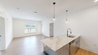 Located at 5736 Oakwood Road in Huntsville, Alabama, this well-appointed 2-bedroom, 2-bathroom residence offers a thoughtfully designed single-floor layout with modern finishes throughout. Light wood-tone flooring flows consistently across the entire space, creating a cohesive and contemporary aesthetic.

The open-concept kitchen and living area serves as the heart of the home. The kitchen features a large peninsula with a granite countertop, undermount sink, and elegant pendant lighting. Warm wood cabinetry is complemented by stainless steel appliances, including a refrigerator, range, and microwave.

The generously sized primary bedroom includes a ceiling fan and direct access to a spacious walk-in closet equipped with wire shelving. The second bedroom is bright and airy, benefiting from a large window with views of surrounding greenery. Both bathrooms are finished with granite-topped gray vanities and matte black hardware accents; one includes a soaking tub, while the other features a glass-enclosed walk-in shower.

A private balcony off the living area extends the living space outdoors, offering open views of the surrounding Huntsville landscape. The clean, neutral color palette and modern fixtures throughout make this a bright, move-in-ready residence.