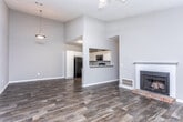 Located on Flat Rock Road in Columbus, Georgia, this single-story home offers a well-designed layout with consistent dark wood-look flooring throughout, creating a cohesive and warm aesthetic across every room. The living room is a standout space, featuring vaulted ceilings, a ceiling fan, a classic fireplace with a white mantle and brick hearth, and a window that brings in natural light. Adjacent to the living room is a spacious dining area with a decorative pendant light and a pass-through view into the kitchen. The kitchen is well-appointed with crisp white shaker-style cabinetry extending to the ceiling, granite-look countertops, a granite tile backsplash, black appliances including a refrigerator, electric range, and built-in microwave, plus a stainless steel sink. The bedrooms are generously sized, with one featuring crown molding, a decorative ceiling fixture, and dual closets, while another includes crown molding and a window with natural light. The bathrooms continue the home's clean aesthetic with white cabinetry, granite countertops, wood-look flooring, and tub-shower combinations. Neutral gray wall tones throughout lend the home a modern, move-in-ready feel.