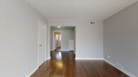 Located at 659 Shaler Blvd in Ridgefield, New Jersey, this single-floor residence offers a straightforward and functional layout with consistent design elements throughout. Rich, dark hardwood floors run continuously across the living areas and bedrooms, providing warmth and character to the space.

The living area is generously sized, featuring neutral gray walls, white trim, and a ceiling-mounted HVAC vent, creating a comfortable and easily customizable environment. Large windows allow natural light to pour in, highlighting the polished hardwood floors. An open passageway connects the living area to a central hall and kitchen beyond, promoting a naturally flowing layout.

The kitchen is equipped with warm oak cabinetry — both upper and lower — paired with granite-look laminate countertops and a deep stainless steel sink. White tile backsplash and walls give the space a clean, practical finish.

The bedrooms continue the hardwood flooring theme, each featuring neutral-toned walls and windows that bring in natural light and outdoor views. The rooms offer a quiet, functional atmosphere well-suited for everyday living.

The bathroom is finished with full white tile walls and mosaic tile flooring, and includes a vanity with oak cabinetry, a mirrored medicine cabinet, and a bathtub with shower — clean and efficiently arranged. Overall, the space presents a cohesive, move-in ready interior.