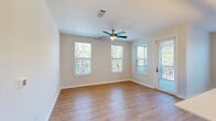 Located at 500 Verdant Way in Charleston, SC, this well-appointed three-bedroom, two-bathroom single-story home offers a thoughtfully designed layout with a clean, modern aesthetic. The open-concept living area seamlessly connects the living room, dining room, and kitchen, which features a large center island with a sleek undermount sink, white shaker cabinetry, stainless steel appliances, and contemporary geometric pendant lighting — all set atop warm hardwood-style flooring that flows throughout the main living spaces. The primary bedroom is generously sized, complete with a ceiling fan, carpet flooring, a walk-in closet with built-in wire shelving, and direct access to a well-appointed en-suite bathroom. The primary bath showcases a dual-sink vanity with white quartz countertops, matte black hardware, framed mirrors, and a glass-enclosed walk-in shower with marble-style tile surround. The two additional bedrooms each offer ceiling fans, natural light from large windows with greenery views, and dedicated closet space. A second full bathroom, a pantry, a laundry room, and five closets in total provide ample storage. The home's light neutral palette, modern fixtures, and abundant windows create a bright, welcoming atmosphere throughout.