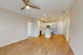 Located at 1387 East Vine Street in Kissimmee, Florida, this well-appointed single-story home offers a thoughtfully designed open-concept floor plan that seamlessly connects the kitchen, dining, and living areas. The kitchen is a standout feature, boasting crisp white shaker cabinetry with brushed nickel hardware, a spacious center island with a white quartz countertop, stainless steel appliances including a French door refrigerator, range, microwave, and dishwasher, all illuminated by stylish pendant lighting. Wide-plank hardwood-style flooring flows throughout the main living areas, while a ceiling fan enhances comfort in the airy living space, which receives natural light through multiple windows. Both bedrooms are carpeted and offer a quiet, comfortable retreat, with the primary bedroom featuring a walk-in closet outfitted with built-in shelving and hanging rods. The two bathrooms are finished with elegant marble-look tile on both floors and walls, and include white vanities with clean countertops. Additional conveniences include a dedicated laundry area, utility room, hallway, and ample closet storage throughout, making this home both functional and stylish.