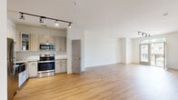 Located at 1000 Sweet Almond Dr in Holly Springs, NC, this 2-bedroom, 2-bathroom residence offers a clean, modern aesthetic across a single floor. The open-concept kitchen and living area serves as the heart of the home, featuring light hardwood-style flooring, crisp white walls, and contemporary track lighting with sleek black fixtures. The kitchen is outfitted with gray shaker-style cabinetry, granite countertops, a classic white subway tile backsplash, and stainless steel appliances including a range and over-the-range microwave. The living area benefits from natural light through a large window, creating a bright and airy atmosphere.

Both bedrooms are carpeted and include ceiling fans, providing comfort and functionality. The primary bedroom connects to its own en-suite bathroom featuring a walk-in shower with white tile surround and brushed gold fixtures, as well as a spacious walk-in closet with multi-tier wire shelving. The second bathroom offers a full tub-shower combination with white tile surround. A second closet provides additional storage. The overall design is cohesive and neutral, making the space move-in ready and highly adaptable to a variety of personal styles.