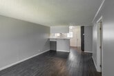 Located at 811 S Fairview St in Santa Ana, California, this single-floor unit offers a clean, updated interior throughout. The open living area is finished with durable wood-look flooring, neutral gray walls, crisp white baseboards, and a textured ceiling, creating a bright and cohesive atmosphere. A peninsula-style kitchen anchors the space, showcasing two-tone cabinetry with slate-blue lower cabinets and white upper cabinets, white quartz-style countertops, a deep stainless steel farmhouse sink, and a stainless steel range — combining modern aesthetics with practical functionality. The kitchen opens toward a windowed dining or entry area with a front door, allowing natural light to flow through. Multiple rooms feature the same consistent wood-look flooring and neutral palette. One room includes a sliding glass door with vertical blinds leading to an outdoor area, as well as a wall-mounted air conditioning unit. Additional rooms offer closet space and windows that bring in natural light. The overall design is clean and move-in ready, with a cohesive modern-neutral style carried consistently throughout the single-level layout.