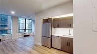 This 430 square foot studio apartment, located at 95 Wall Street in New York City, offers a contemporary living space designed for efficiency and comfort. The open floor plan maximizes the use of space, creating a seamless flow between living areas. The apartment features sleek, modern finishes throughout, with pristine white walls and warm, honey-toned hardwood flooring that adds warmth and character.

Large windows dominate one wall, flooding the space with natural light and offering views of the surrounding urban landscape. These windows not only brighten the interior but also create a sense of spaciousness in the compact layout. A wall-mounted air conditioning unit beneath the window provides climate control.

The kitchen area, while compact, is equipped with high-end stainless steel appliances, including a full-sized refrigerator, suggesting no compromise on functionality despite the space constraints. Clean lines and minimalist design are evident in the cabinetry and overall aesthetic.

The living area is versatile, able to accommodate various furniture arrangements for lounging, dining, and sleeping. Built-in closets with white doors offer valuable storage space, maintaining the apartment's clean and uncluttered appearance. Recessed lighting in the ceiling provides even illumination throughout the space.

This studio apartment exemplifies smart urban living, where every square foot is utilized effectively to create a comfortable and stylish home in the heart of Manhattan.