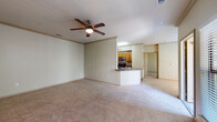 This single-story residence offers a well-organized layout with a comfortable, neutral aesthetic throughout. The open-concept living area is generously sized, finished with wall-to-wall carpet and accented by crown molding and a ceiling fan with light kit. Natural light fills the space through large windows and a sliding glass door that provides outdoor access, enhancing the bright, airy feel of the room.

The kitchen is efficiently designed in a galley configuration, featuring stainless steel appliances including a refrigerator, electric range, microwave, and dishwasher. Warm wood-toned cabinetry pairs with dark granite-style countertops, and a peninsula with a sink separates the kitchen from the living area, providing a casual bar-style seating option. A walk-in pantry closet offers additional storage within the kitchen.

The bedrooms are carpeted and well-lit by windows with views of surrounding greenery, each equipped with ceiling fans. The primary bathroom includes a double-sink vanity with wood cabinetry, a large mirror with vanity lighting, and a tiled tub-shower combination. A second bathroom features similar cabinetry and a toilet, accessible from a hardwood-style floored hallway shared between rooms.