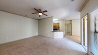 This single-story residence offers a well-organized layout with a comfortable, neutral aesthetic throughout. The open-concept living area is generously sized, finished with wall-to-wall carpet and accented by crown molding and a ceiling fan with light kit. Natural light fills the space through large windows and a sliding glass door that provides outdoor access, enhancing the bright, airy feel of the room.

The kitchen is efficiently designed in a galley configuration, featuring stainless steel appliances including a refrigerator, electric range, microwave, and dishwasher. Warm wood-toned cabinetry pairs with dark granite-style countertops, and a peninsula with a sink separates the kitchen from the living area, providing a casual bar-style seating option. A walk-in pantry closet offers additional storage within the kitchen.

The bedrooms are carpeted and well-lit by windows with views of surrounding greenery, each equipped with ceiling fans. The primary bathroom includes a double-sink vanity with wood cabinetry, a large mirror with vanity lighting, and a tiled tub-shower combination. A second bathroom features similar cabinetry and a toilet, accessible from a hardwood-style floored hallway shared between rooms.