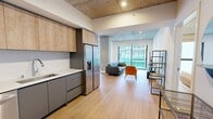 This contemporary apartment, unit #801 in TENTEN Downtown, offers a harmonious blend of style and functionality within its 1210 square feet. The open-concept design maximizes space, featuring a combined kitchen and living area. The kitchen boasts modern appliances, including a stainless steel refrigerator and built-in microwave, complemented by two-tone cabinetry in light wood and gray.

The apartment's three bedrooms provide ample space for rest and privacy, with the primary bedroom measuring a generous 210 square feet. Two well-appointed bathrooms feature sleek fixtures, including a glass-enclosed shower and LED-lit mirror.

Throughout the space, industrial-chic elements like exposed concrete ceilings contrast with warm wooden floors, creating a sophisticated urban aesthetic. Large windows flood the rooms with natural light and offer city views. A private balcony with glass railings extends the living space outdoors.

The unit's design emphasizes clean lines and a neutral color palette, accented by pops of color in the furniture. Built-in storage solutions and minimalist decor maintain a clutter-free environment. As part of a larger complex, residents likely have access to shared amenities, making this apartment an ideal urban retreat in the heart of downtown.