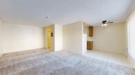 Located at 550 Yucca Ave in Barstow, California, this compact single-floor unit offers an efficient and practical layout well-suited for straightforward, comfortable living. The space is thoughtfully organized to maximize its footprint across one level.

The kitchen is a standout functional area, outfitted with warm-toned natural wood cabinetry — both upper and lower — providing ample storage. White laminate countertops run along the base cabinets, which include a stainless steel double-basin sink with a standard faucet. A white range and a full-size refrigerator complete the kitchen's appliance package. Light tile flooring runs throughout the kitchen area, contributing to an easy-to-maintain surface. A wall-mounted heating and cooling unit provides climate control.

The main living area transitions to plush wall-to-wall carpeting, offering a softer feel underfoot. A ceiling fan with an integrated light fixture is centrally mounted, aiding air circulation throughout the space. Textured ceilings are consistent throughout, and neutral wall tones keep the interior feeling open and clean.

The bathroom includes a full bathtub and shower combination with white surround walls, providing a clean and functional bathing space. Overall, this unit delivers a no-frills, practical living environment with essential amenities in a straightforward, easy-to-navigate layout.