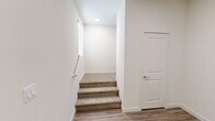Located at 2601 Wagon Wheel Rd in Oxnard, California, this tri-level home offers three bedrooms, four bathrooms, and an expansive layout spread across three floors. The main level commands the majority of the living space and showcases an open-concept kitchen and living area with light wood-look flooring, recessed lighting, and elegant pendant lights. The kitchen is equipped with stainless steel appliances, grey cabinetry, a white quartz countertop island with an integrated sink, and access to a dedicated pantry. Upper levels are connected by two staircases with white-railed banisters and feature plush carpeted bedrooms filled with natural light from large windows. The primary bedroom includes a walk-in closet with built-in shelving and an en-suite bathroom boasting a dual-sink vanity with modern grey cabinetry and a glass-enclosed walk-in shower with white tile surround. Additional bedrooms offer generous proportions and easy access to well-appointed bathrooms. A private balcony overlooks a landscaped courtyard, providing a peaceful outdoor retreat. The ground level includes a spacious covered parking structure. Clean neutral tones and contemporary finishes throughout lend the home a bright, modern aesthetic.