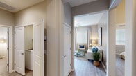 This thoughtfully designed single-story residence offers a seamless open-concept layout connecting the living, dining, and kitchen areas, creating a bright and cohesive living environment. Light wood-style flooring flows throughout, complementing the neutral warm-toned walls and white trim that lend the space a clean, contemporary feel.

The kitchen is outfitted with crisp white cabinetry, granite-style countertops, stainless steel appliances including a range, microwave, and dishwasher, and a double-basin sink positioned beneath a large window that brings in generous natural light. A spacious breakfast bar with seating opens directly to the dining and living areas, making the kitchen ideal for both casual meals and entertaining.

The living room features tall ceilings, large windows dressed with blinds and floor-length curtains, and ample room for comfortable seating arrangements. The primary bedroom is anchored by a bold navy accent wall, providing a striking focal point, and is served by an en-suite bathroom with a glass-enclosed shower, granite vanity, and direct access to a walk-in closet. Additional bedrooms are well-sized, each offering natural light through large windows and ceiling fans. A dedicated laundry area and a hallway with interior storage complete this functional and stylish residence.