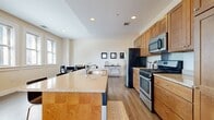 This thoughtfully designed 2-bedroom, 2-bathroom residence offers a comfortable and functional single-floor layout. The open-concept living area serves as the heart of the home, where the kitchen, dining, and living spaces flow seamlessly together. The kitchen is equipped with warm-toned wood cabinetry, stainless steel appliances including a gas range, microwave, and refrigerator, and a large granite-topped island with seating — ideal for both cooking and casual dining. Light hardwood flooring runs throughout, lending a cohesive, airy feel to the entire space. The dining area accommodates a full-sized table and benefits from natural light streaming through double windows with blinds. The spacious living room features multiple windows that fill the room with daylight, creating a bright and welcoming atmosphere. The generously sized primary bedroom includes a trio of windows and ample floor space, while the second bedroom offers a cozy, well-proportioned retreat. Both bathrooms are clean and functional, with one featuring a full soaking tub and shower combination with tile flooring. Neutral warm tones on the walls complement the natural wood floors throughout, creating a calm and inviting ambiance across the entire residence.