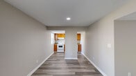 This single-story unit offers a clean, functional layout with a neutral color palette and wood-look laminate flooring carried consistently throughout. The living area is bright and open, anchored by a set of French doors that allow natural light to fill the space and provide views of the outdoors. A partial-wall divider separates the living area from the kitchen, which features warm honey-toned cabinetry, laminate countertops, a double-basin stainless steel sink, a white electric range, and a dishwasher. Recessed lighting provides focused illumination in the kitchen area.

The bedrooms are well-proportioned, each with windows fitted with horizontal blinds that allow for adjustable natural light. At least one bedroom includes a sliding-door closet with interior shelving, offering practical storage. The full bathroom includes a single-sink vanity with a light-toned countertop, a lighted mirror, and a tub-shower combination. Textured ceilings are present in several rooms. The overall ambiance is clean, neutral, and move-in ready, with a straightforward layout that maximizes functionality throughout the unit.
