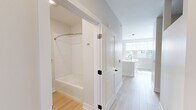 Located at 26 Jerome Ave in Bloomfield, Connecticut, this thoughtfully designed one-bedroom, one-bathroom residence makes efficient use of its compact footprint with a clean, modern aesthetic. Light wood-style flooring flows throughout the space, complementing the crisp white walls and creating a bright, cohesive atmosphere.

The kitchen serves as the centerpiece of the home, showcasing a large white waterfall-edge island with an integrated sink, ideal for both meal preparation and casual dining. Warm-toned wood grain cabinetry lines the walls, providing ample storage, while stainless steel appliances — including a refrigerator, electric range, and over-the-range microwave — deliver a polished, functional cooking environment. A white subway tile backsplash adds a clean, contemporary touch, and pendant lighting overhead enhances the open feel of the space.

The bathroom is finished with the same light wood-style flooring and features a full soaking tub with a curved shower rod and white tiled surround, a wood-accented vanity with a white countertop, and tasteful chrome fixtures. The neutral palette throughout keeps the space feeling open and airy.

Natural light filters in through windows that offer views of the surrounding neighborhood, adding warmth and vitality to this well-appointed Bloomfield residence.